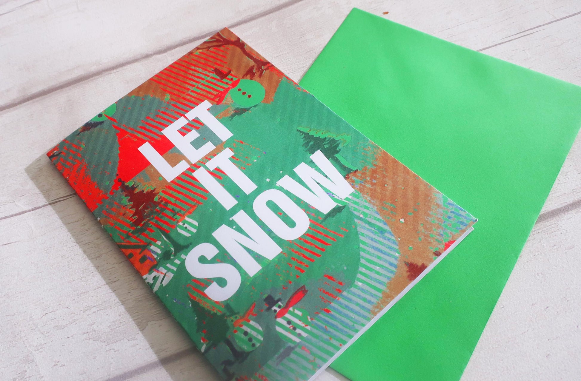 Colorful greeting card with 'Let It Snow' text on a white surface