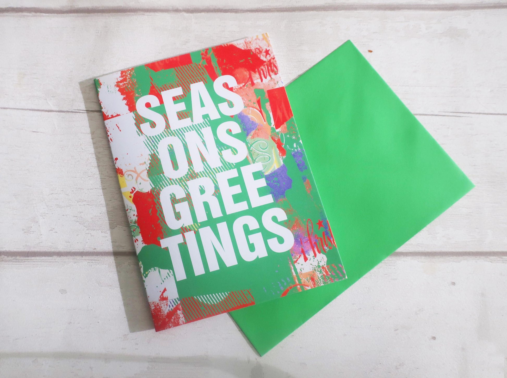 Colorful greeting card with 'Seasons Greetings' text on a wooden surface