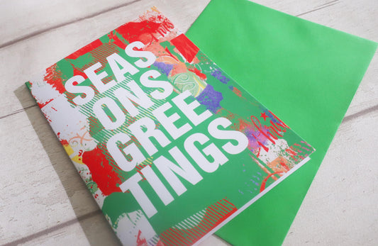 Colorful card with 'SEASONS GREETINGS' text on a wooden surface