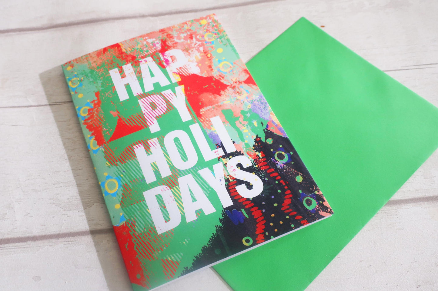 Colorful greeting card with 'Happy Holly Days' text on a wooden surface
