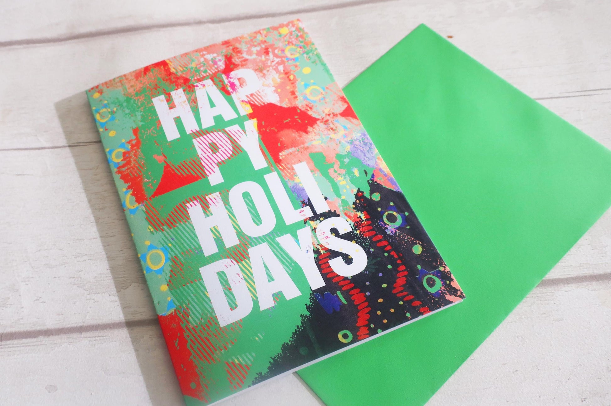 Colorful greeting card with 'Happy Holly Days' text on a wooden surface