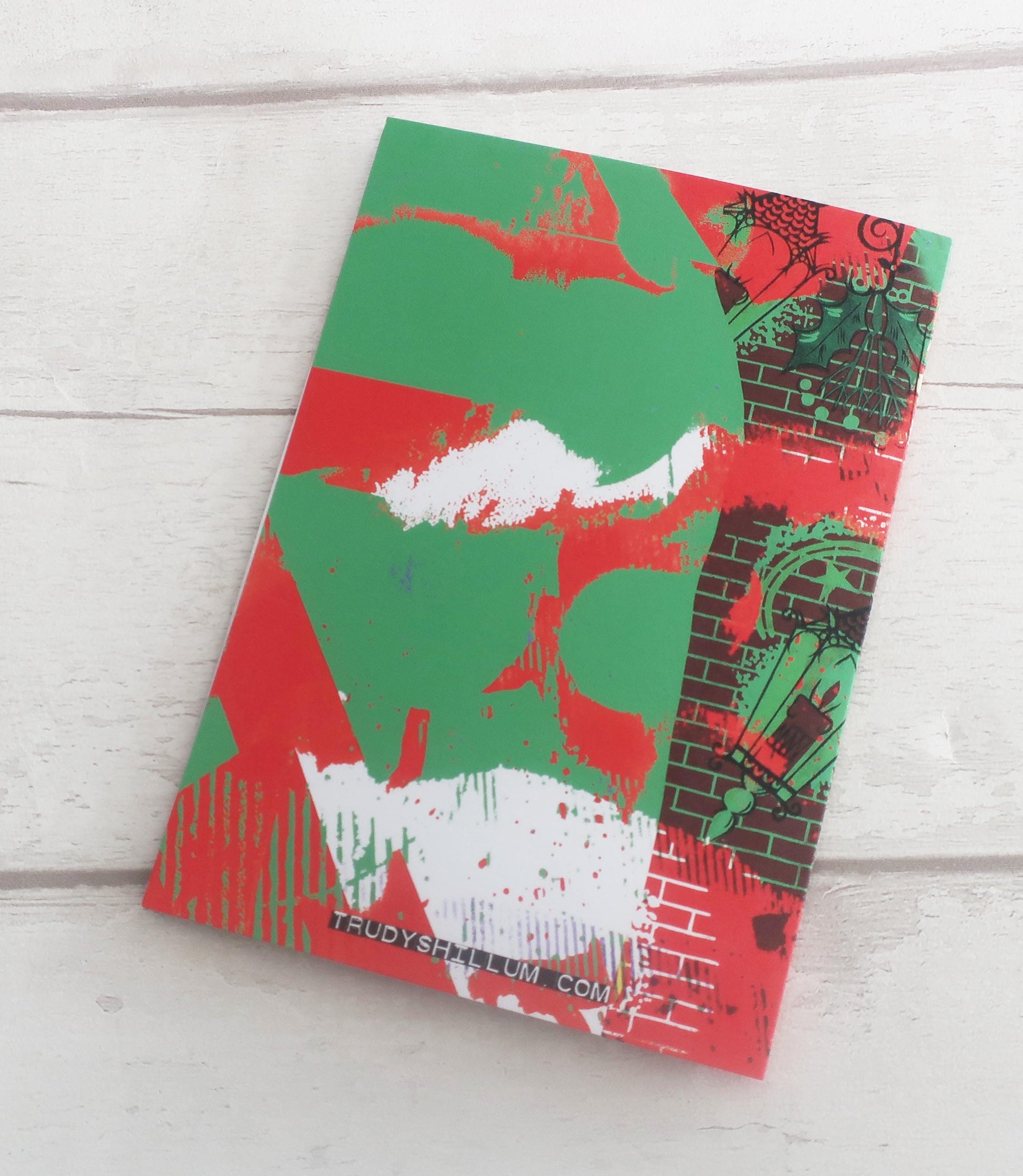 Card with green and red abstract design on a light wooden surface