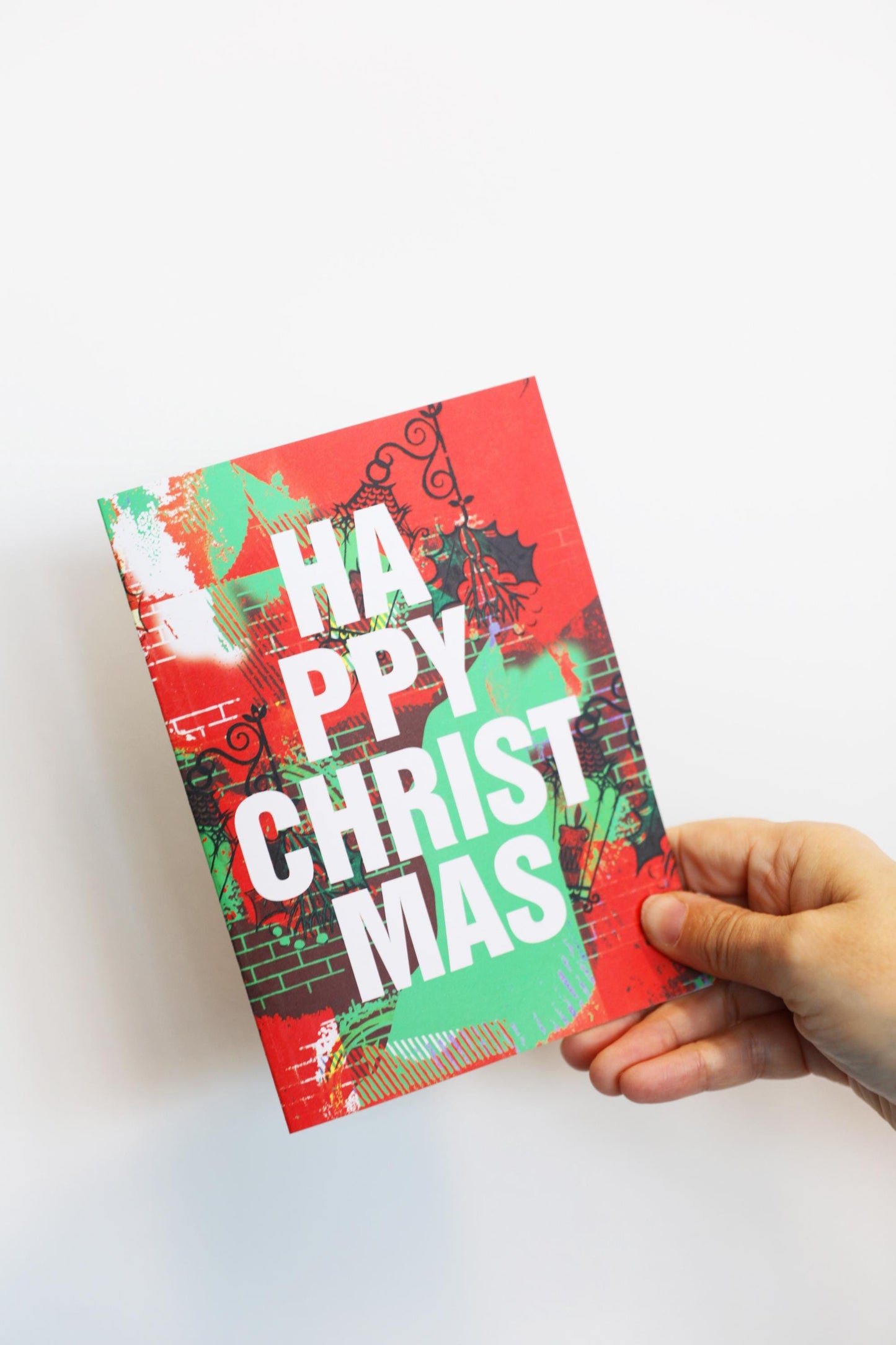 Hand holding a colorful 'Happy Christmas' card against a white background