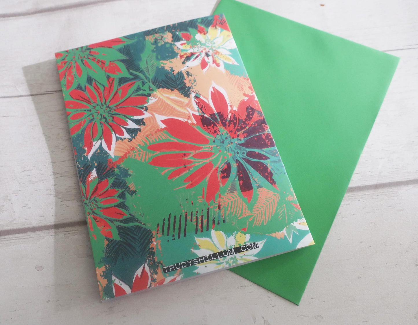 Colorful floral card with a green cover on a light wooden surface