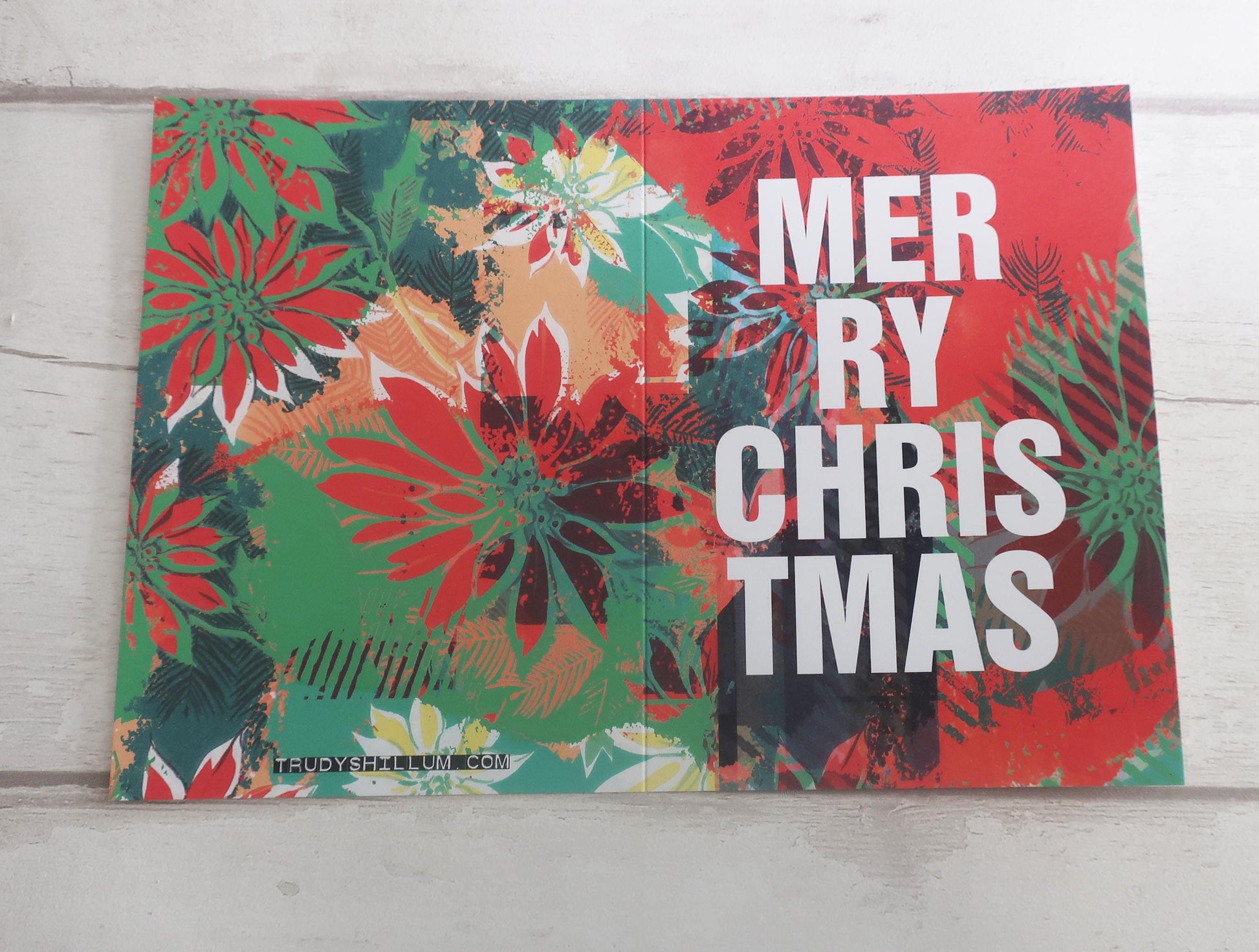 Colorful Christmas-themed decorative card with 'Merry Christmas' text on a wooden background.