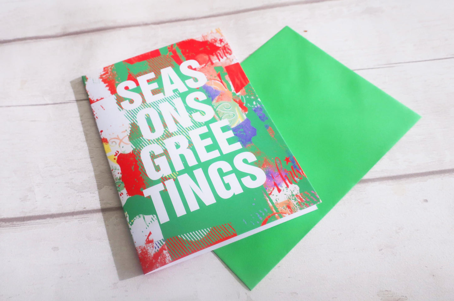 Colorful greeting card with 'Season's Greetings' text on a wooden surface