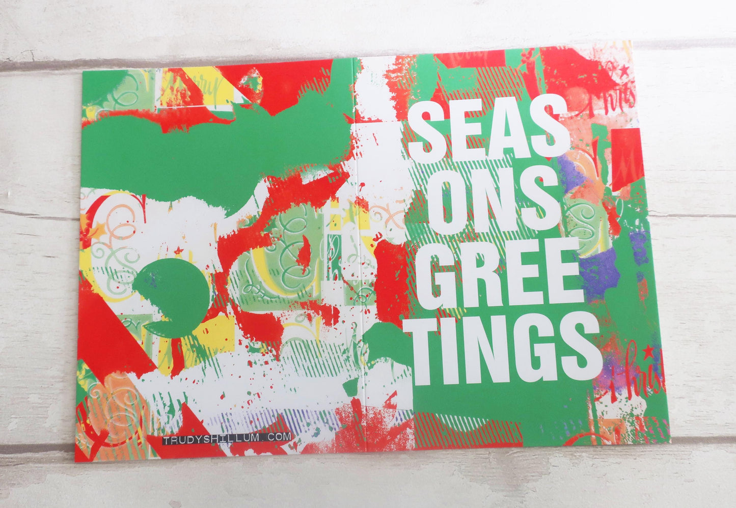 Colorful greeting card with 'Seasons Greetings' text on a wooden surface