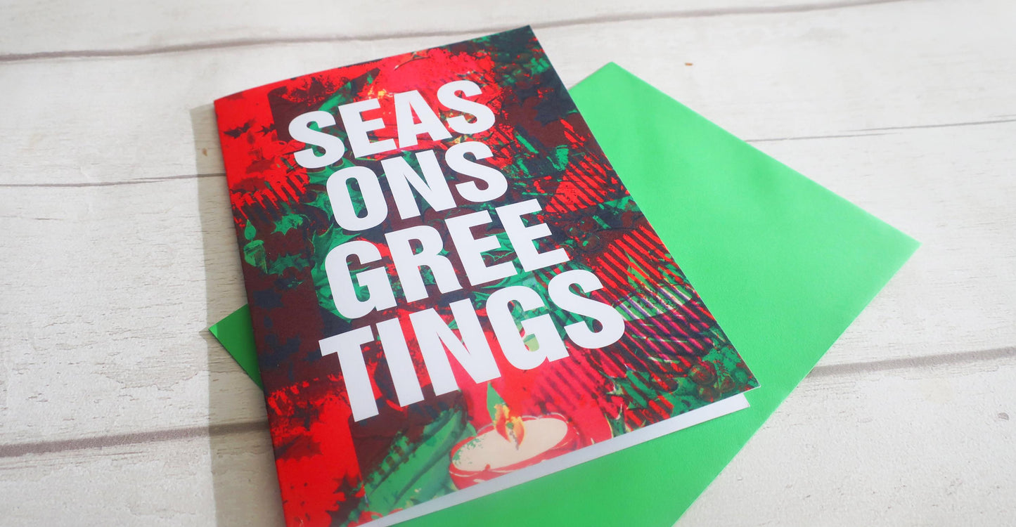 Greeting card with 'Seasons Greetings' text on a white wooden surface