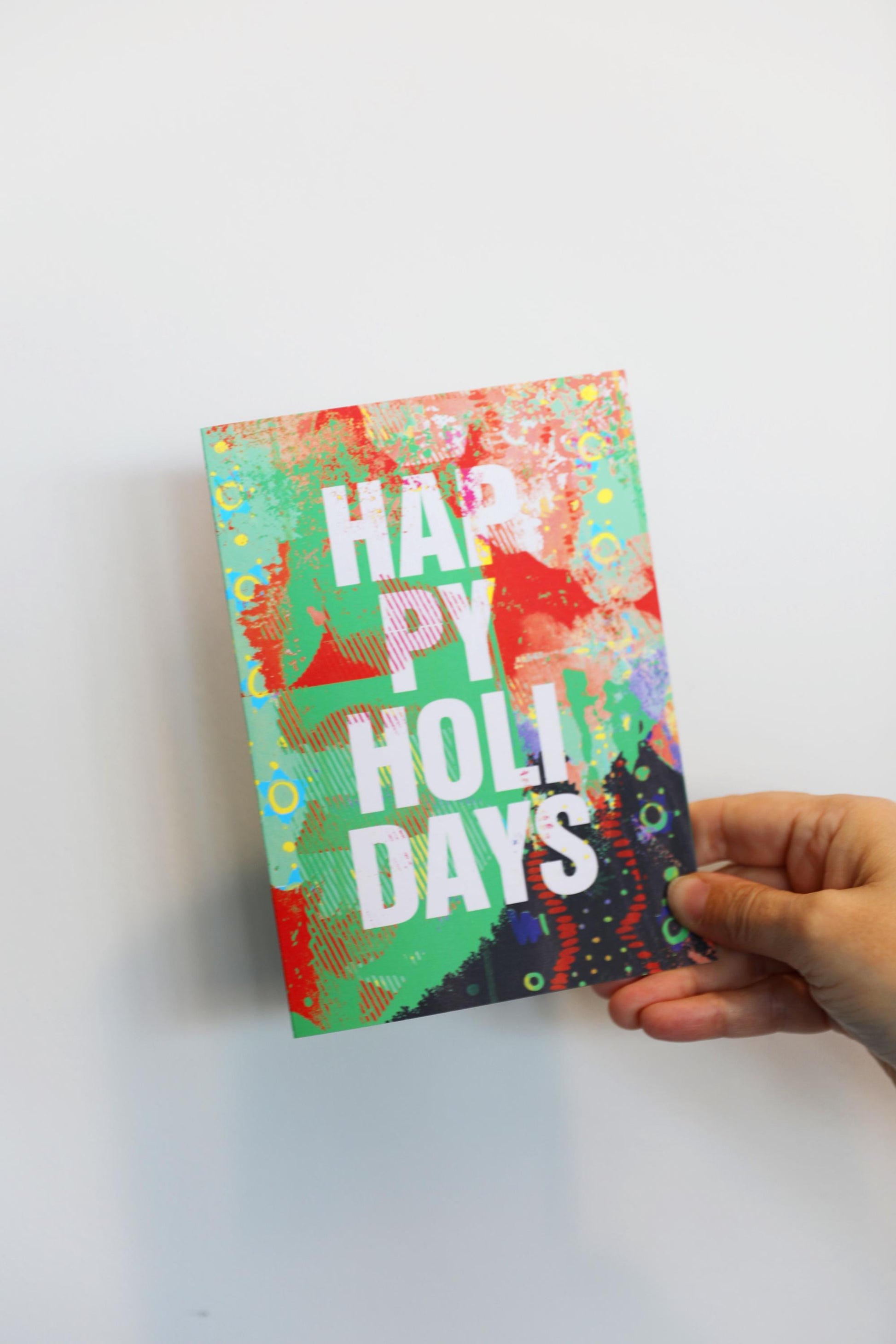 Colorful card with 'Happy Holidays' text held by a hand on a white background