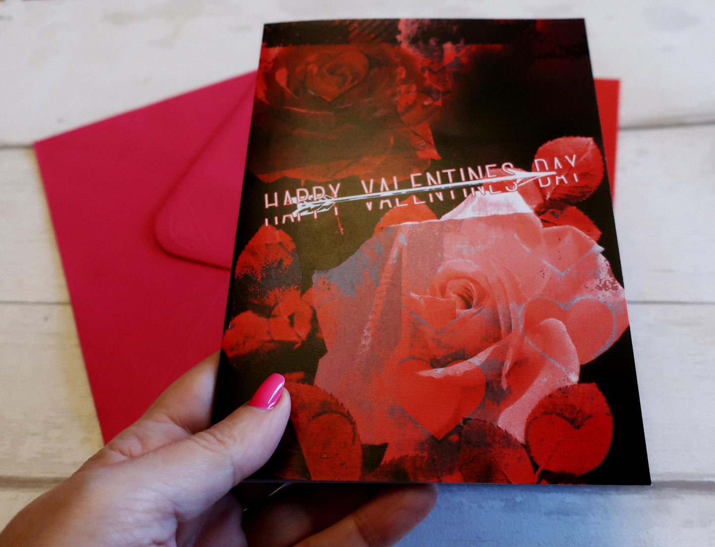 Valentine's Day card with red roses and a hand holding it.