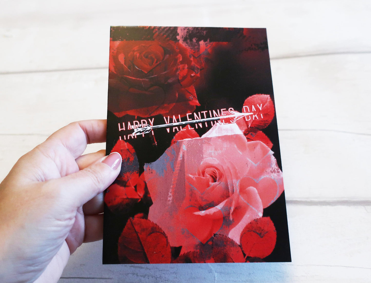 Valentine's Day card with red roses and 'Happy Valentine's Day' text held by a hand on a white background.
