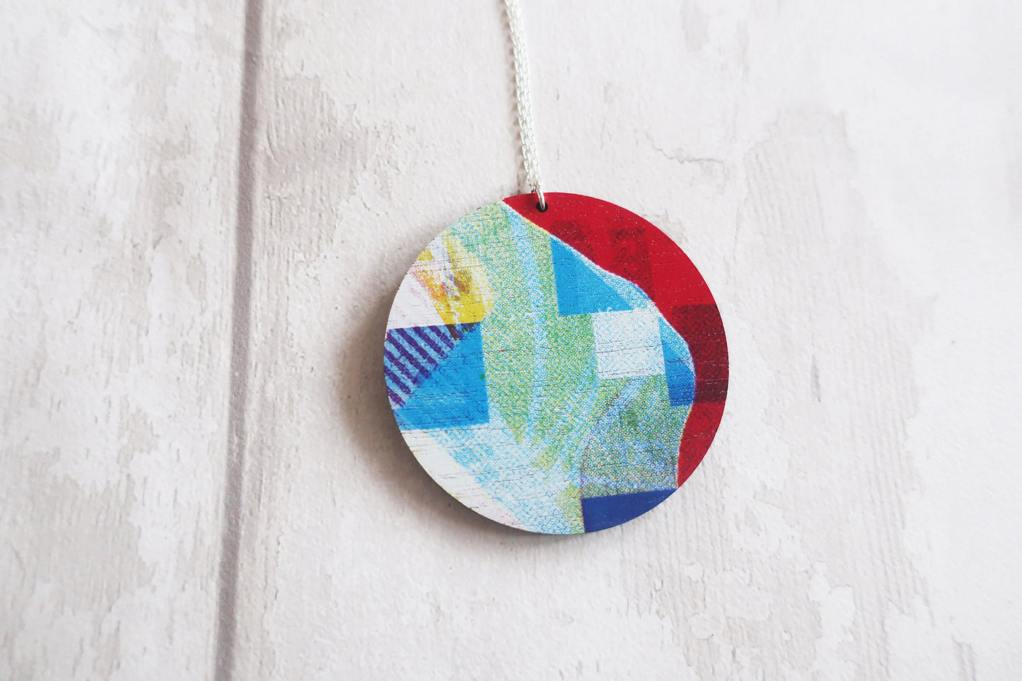 Colorful circular pendant with a patchwork design hanging on a white background