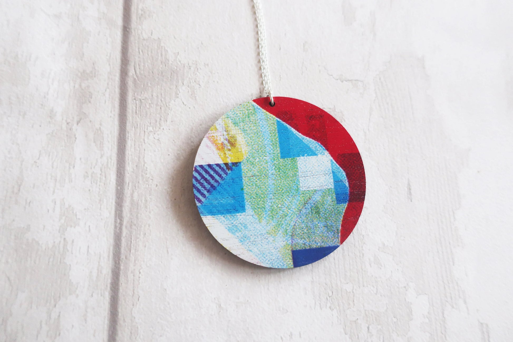 Colorful circular pendant with a patchwork design hanging on a white background