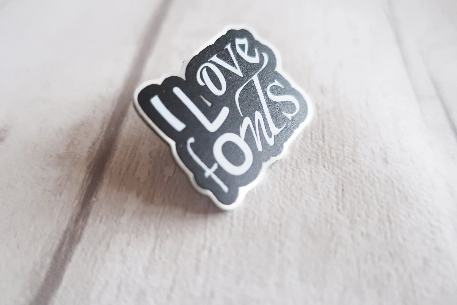 Pin badge with 'I Love Fonts' text on a textured surface