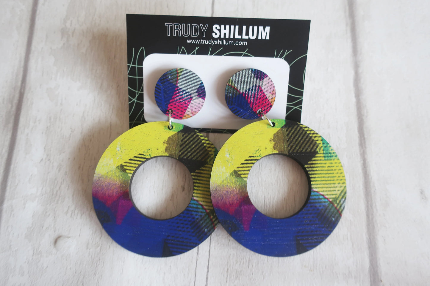 Colorful earrings on a white surface with a Trudy Shillum card in the background.