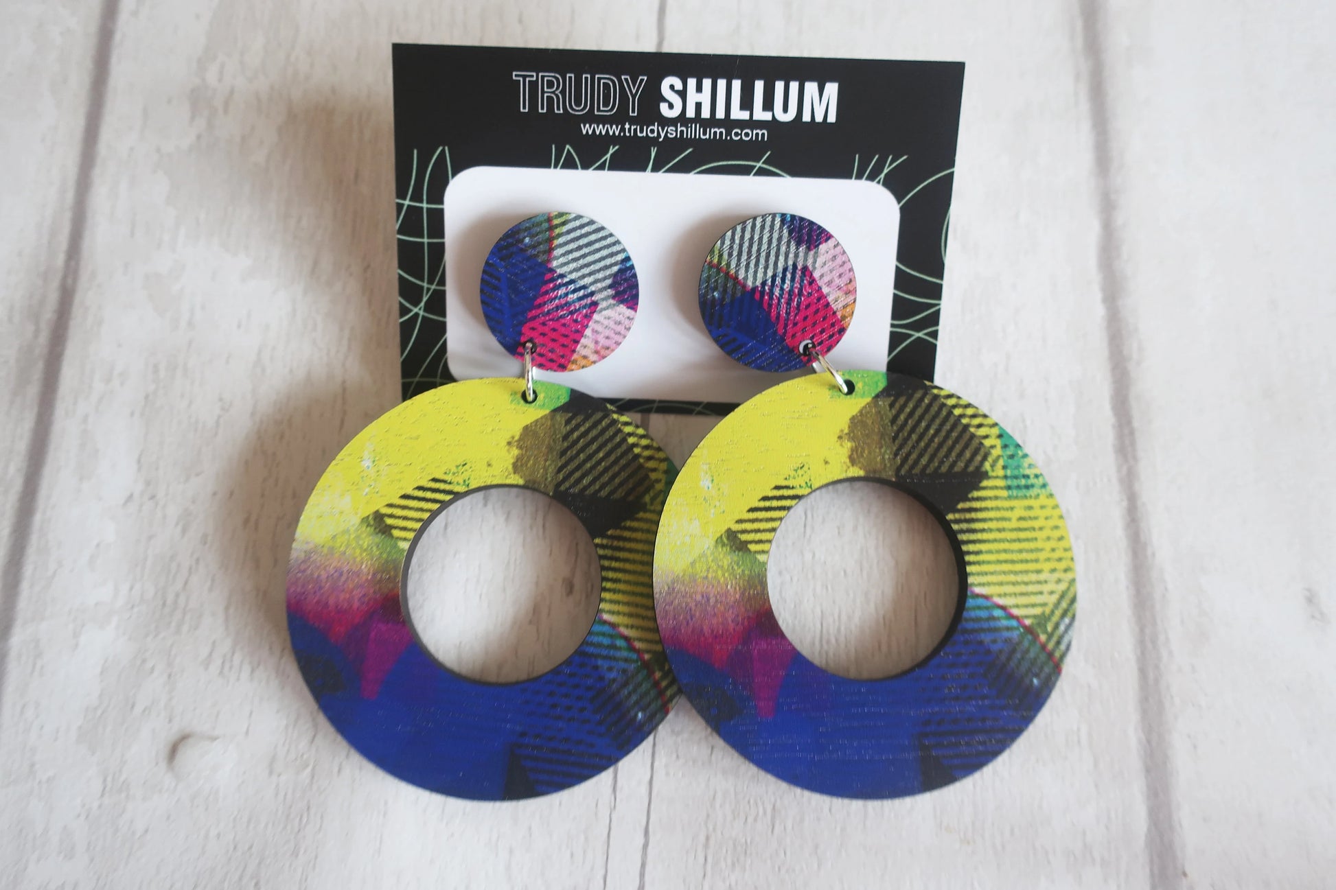 Colorful earrings on a white surface with a Trudy Shillum card in the background.
