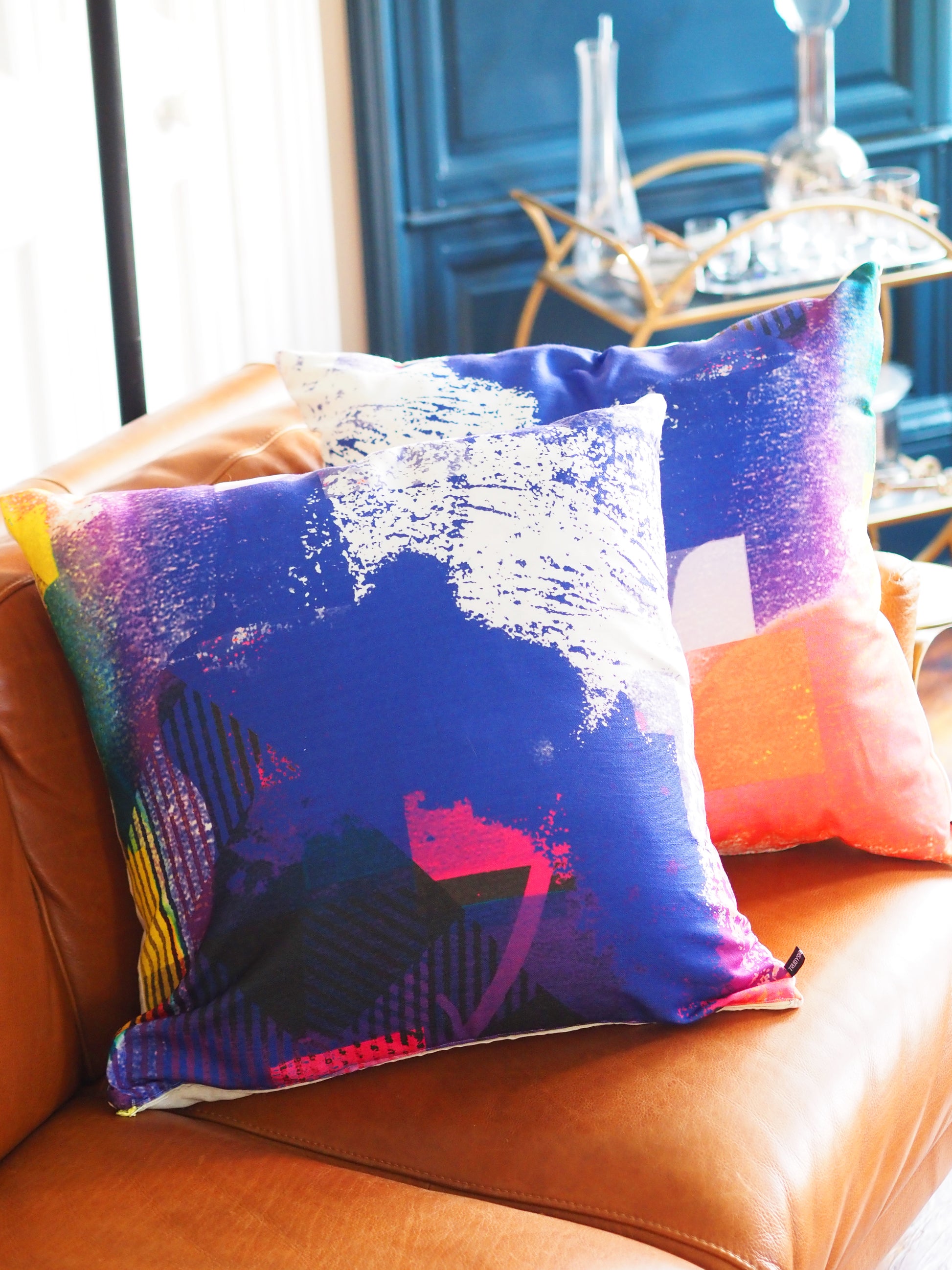 Colorful decorative pillow on a brown leather couch with a blurred background