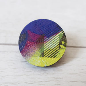 Purple and yellow round wooden pin badge